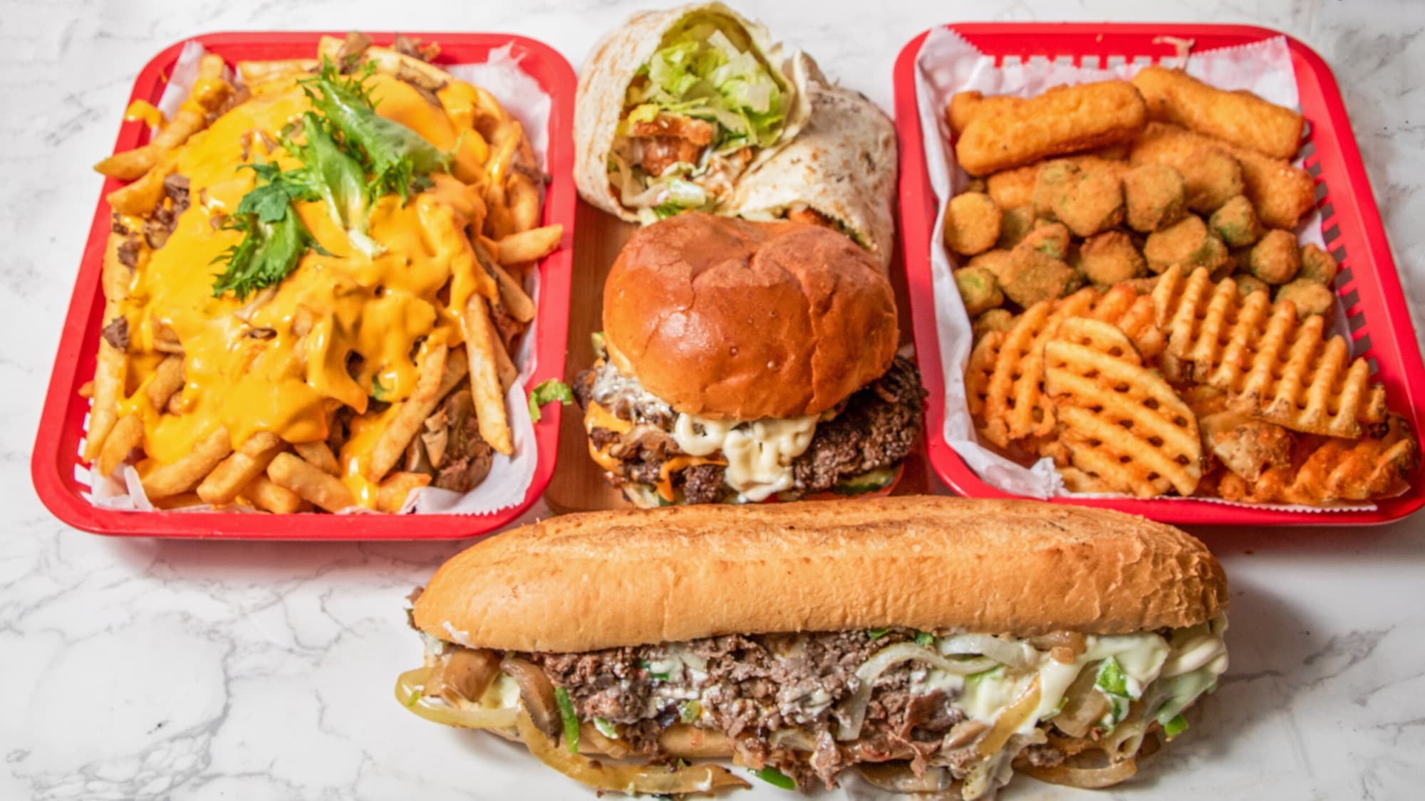 A spread of Moe'z signature cheesesteaks, burgers, and sides